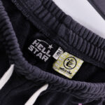 Close-up view of the branding labels and authenticity tag on a pair of black Hellstar Studios Records fleece shorts.
