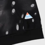 Close-up of the Hellstar Studios Records black tracksuit featuring branded triangle logo and unique dot graphic detail.