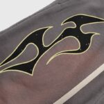 Close-up view of a brown Hellstar Studios short featuring a prominent black and yellow tribal flame graphic design detail.