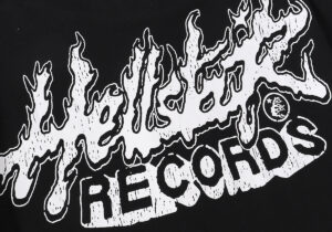Close-up of the Hellstar Studios Records logo graphic with a flame design on a black cotton t-shirt fabric.