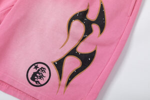 Close-up view of Hellstar Studios Records pink shorts featuring a bold black and gold graphic flame print design.