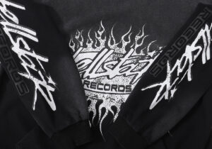 Close-up view of the black Hellstar Studios Records vintage tracksuit featuring unique white graphic flame branding.