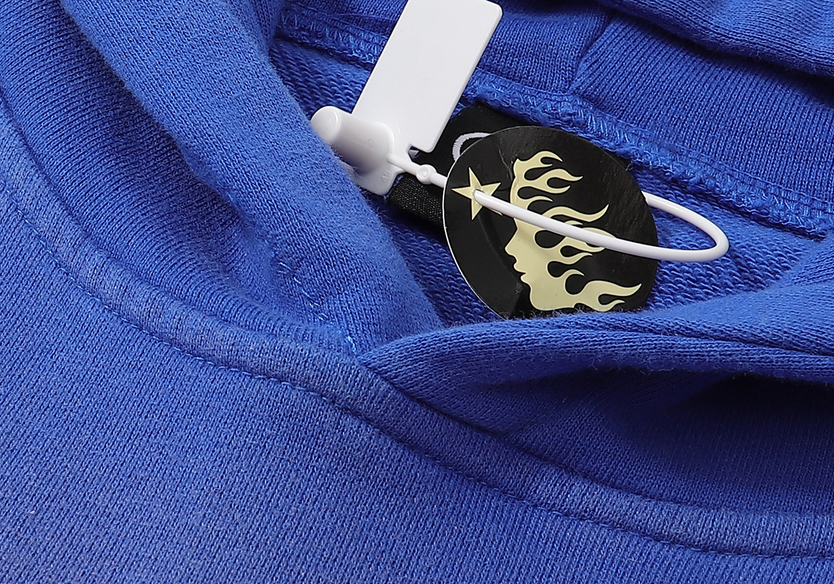 Close up of the brand tag on a blue Hellstar Studios Records Yoga Hoodie showing the iconic logo and plastic seal.