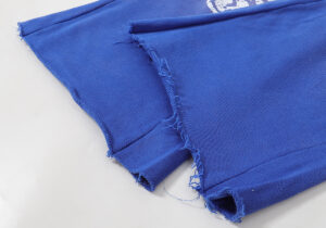 A close-up detail shot of the hem on a pair of blue Hellstar Studios Records yoga sweatpants made in Los Angeles.