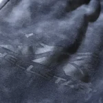 Close-up view of the Hellstar Studios logo featured on the premium washed grey fabric of the vintage-style tracksuit.