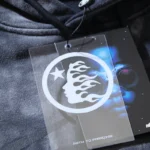 Detail of the Hellstar Studios washed grey tracksuit, showing the iconic logo hang tag and premium fabric texture.