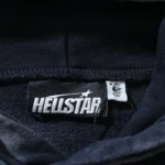 Close-up view of the Hellstar Studios branding tag sewn into the collar of a premium washed grey cotton hoodie.