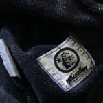Detail view of the Hellstar Studios branded neck label on the authentic washed grey cotton tracksuit.