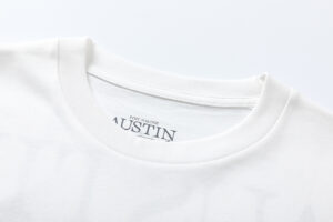 Close-up view of the ribbed neckline on the white Hellstar Studios x Post Malone Austin T-shirt with branded print