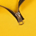 Close-up view of the metallic quarter-zip detail on a vibrant yellow Hellstar Studios casual cotton zipper sweater.