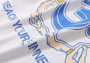 Close-up of the Hellstar Studios Yoga white T-shirt featuring blue and cream screen-printed graphic detailing.