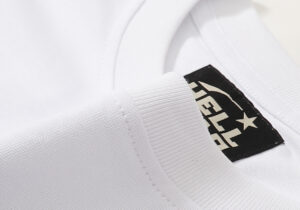Close-up view of the interior collar tag on the white Hellstar Studios Yoga T-Shirt featuring brand logo details.