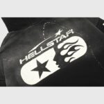 Back view of the Hellstar Studios black zip-up hoodie featuring a white graphic print with stars and flames design.