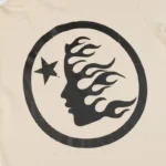 Close-up of the Hellstar Studios beige zipper sweater featuring a black graphic print of a face and star inside a circle