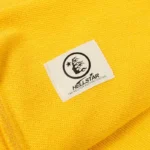 Close up view of the yellow Hellstar Studios zipper sweater showing the branded authentication label detail.