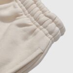 Close-up view of the adjustable elastic waistband detail on the Hellstar If You Don’t Like Us Beat Us cream sweatpant.