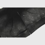 Close-up view of the front pocket and paint splatter details on a black Hellstar The Path to Paradise zip-up hoodie.