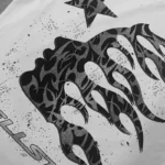 Detailed view of the black graphic screen print featuring a glitter flame design on the Hellstar Thorn white T-shirt.