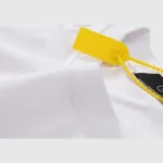Close-up view of the white Hellstar Thorn Glitter T-shirt featuring a prominent yellow merchandise security tag.