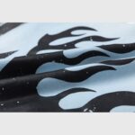 Close-up of light blue fabric with a black flame print and white speckled detail