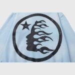 Close-up view of the Hellstar Uniform Hoodie in baby blue featuring a signature circular flame graphic logo.