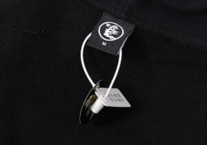 Hellstar Uniform Hoodie black fabric detail showing the brand logo on the clothing tag and attached product size label