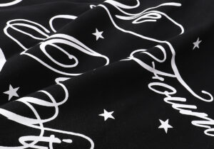 Close-up view of the white graphic print featuring artistic lettering and small stars on a black Hellstar Victory Hoodie.