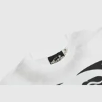 Close-up view of the Hellstar Warm Up T-shirt neck label showing the branded tag on a premium white 100% cotton tee.