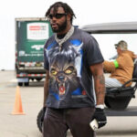Stylish man wearing a black Hellstar Wolf T-shirt featuring a detailed snarling wolf graphic print outdoors.