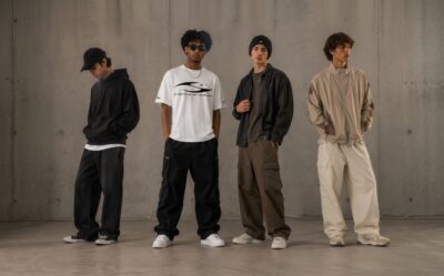 Four young men posing against a grey wall showcasing Hellstar streetwear compared with different urban fashion styles.